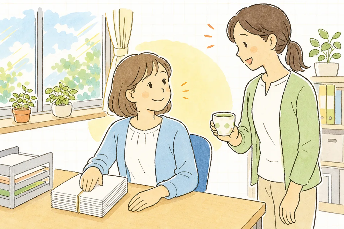 発送の準備を終えた事務室で、きれいにそろった封筒の束を前に、ほっとした笑顔で同僚と目を合わせている介護事業所の事務担当者